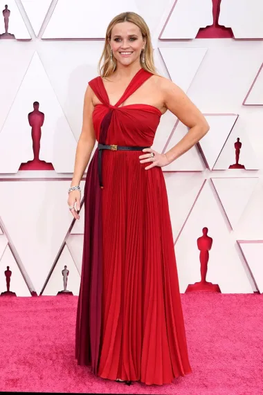 Prekrasna oskarovka i južnjačka slatkica, glumica Reese Witherspoon prva je na našoj listi. Naime, ova je velika holivudska dama na Oscare 2021. došla u ovoj vatreno crvenoj plisiranoj haljini s crnim remenom oko struka te je oduševila i publiku i modne stručnjake svojim izgledom. Crvenu haljinu potpisala je modna kuća Christian Dior, a mnogi su ju proglasili neobičnim i hrabrim odabirom. Naime, Reese je inače poznata po tome da bira neutralnije tonove haljina te ju do sada nismo imali prilike vidjeti u mnogo crvenih toaleta. Zanimljivo je i to da je vlastitog Oscara Reese također primila u Diorovoj haljini - legendarnom vintage modelu s tisućama perlica i bisera. 