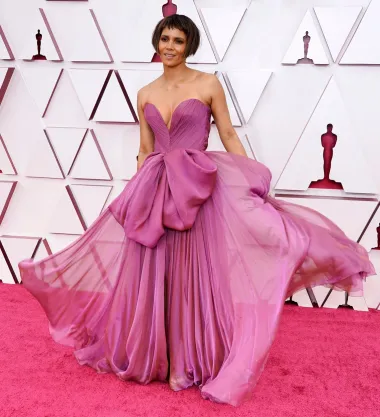 Još jedna oskarovka na našoj listi je i genijalna Halle Berry. Ova tamnoputa ljepotica na dodjeli Oscara 2021. pojavila se u ovoj lepršavoj haljini boje ciklame s golemom mašnom na struku i dubokim dekolteom, a plijenila je pažnju i neobičnom kratkom frizurom s kakvom ju još nismo vidjeli. Halleina haljina odmah je bila proglašena jednom od najdojmljivijih te večeri, a potpisala ju je slavna talijanska kuća Dolce &amp; Gabbana. 