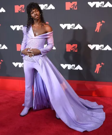 Kada govorimo o ovogodišnjoj modi, na crvenim se tepisima doista moglo vidjeti svašta, no reper Lil Nas X sve nas je oborio s nogu svojim ekscentričnim outfitima. Naime, ovaj megauspješni mladi glazbenik na dodjeli se MTV Music Awardsa pojavio u ovom lila kompletu sakoa s golemim plaštom u stilu haljine, kristalima i s vrlo bujnom fudbalerkom. Iako su ga mnogi proglasili za najekscentričnije odjevenog glazbenika godine, za mnoge je postao i fashion ikona koja pomiče modne granice. 