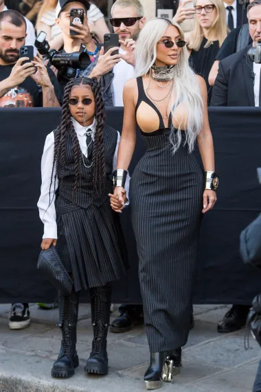 Kim Kardashian na reviji se pojavila zajedno s kćeri North West. 41-godišnja reality zvijezda pokazala je zavidnu figuru u pripijenoj prugastoj haljini s nude gornjim dijelom u obliku grudnjaka, koja je ujedno dio nove kolekcije. Sve je začinila sa statment nakitom, uključujući glomazni choker i ogrlicu koja izlazi iz nosa, a isti modni dodatak u obliku piercinga nosila je i devetogodišnja North. 
