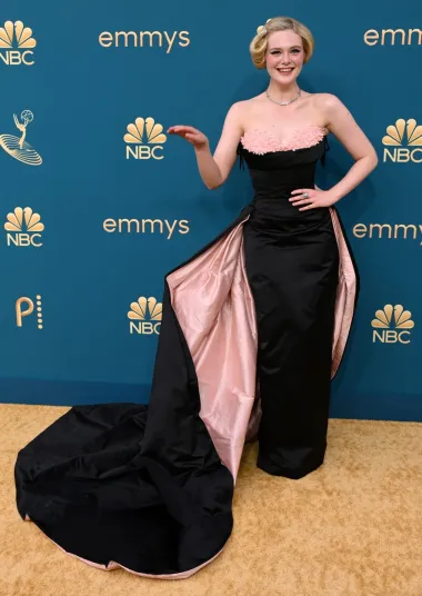 Elle Fanning nosila je romantičnu crno-ružičastu ručno rađenu haljinu Sharon Long inspiriranu 50-im godinama prošlog stoljeća. No cijeli outfit je podsjećao na estetiku sredine prošlog stoljeća jer je imala i posebnu frizuru koja je bila popularna u to vrijeme.