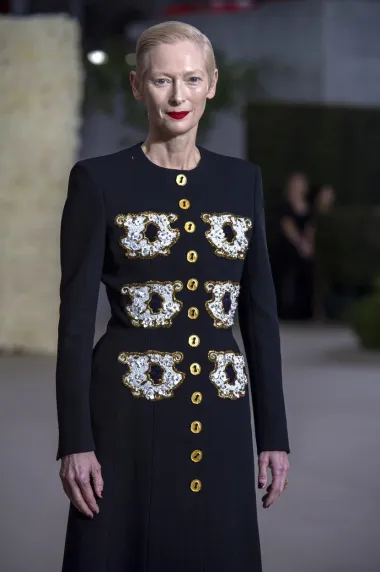  Tilda Swinton poznata je po tome kako je uvijek drugačija na crvenom tepihu. Ovaj put odlučila se za dugu haljinu s potpisom talijanskog brenda Schiaparelli. Haljina tamne boje dojmljiva je zbog zlatnih gumba i neobičnog uzorka, a 62-godišnjakinja ju je odlično &apos;isfurala&apos;. 