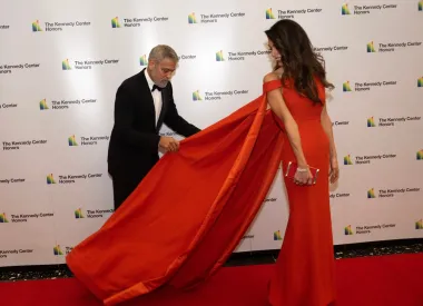 Holivudski šarmer  hrabro se uhvatio ukoštac sa šlepom svoje drage i popravio ga kako bi ona na fotografiji izgledala besprijekorno. Predivnu crvenu haljinu zbog koje je Clooney imao pune ruke posla potpisuje Valentino.