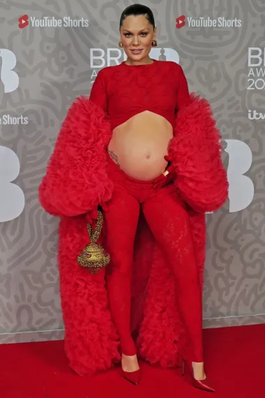 Britanska pjevačica Jessie J na crvenom tepihu BRIT Awardsa prije nekoliko dana. Za ovu  je priliku odabrala crveni čipkasti, rastezljivi i uski kombinezon, s velikim otvorom za trbuh te ogrtač od nabranog tila i crvene salonke. 