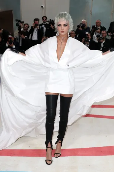 Cara Delevigne odala je počast slavnom dizajneru pojavivši se u jednostavnom outfitu s njegovim zaštitinim znakovima: bijeloj košulji haljini, crnim kožnim rukavicama i naočalama. 