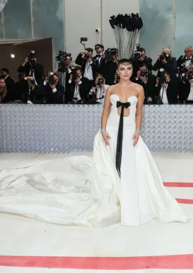 Glumica Florence Pugh izabrala je glamurozan, ali dramatičan look s potpisom modne kuće Valnetino - odim bijele haljine s crnom mašnom, najveću pažnju plijenio je njezin ukras na obrijanoj glavi, pa je tako glumica pokazala i svoju novu frizuru. 