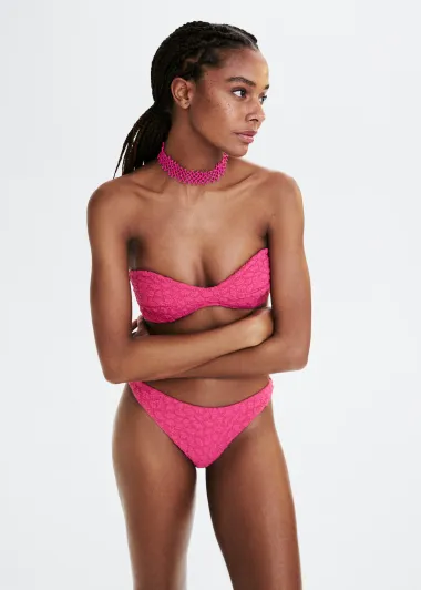 Bikini u ružičastoj boji ističe se zbog jarke boje. Gornji dio nema naramenica, a materijal ima vrlo bogatu teksturu.