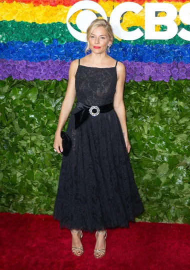 Sienna Miller nosila je crnu čipkastu Miu Miu koktel haljinu u A-silueti s crnim baršunastim remenom ukrašenim Swarovski kristalima na dodjeli Tony Awards 2019. u Radio City Music Hallu u New Yorku.