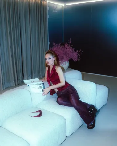 Miach nosi tamnocrveni prsluk i prozirne mrežaste hlače u retro stilu 90-ih, koje kombinira s platformama i upečatljivim makeupom. Look zaokružuju visoki rep, stvarajući balans između minimalizma i edgy estetike.