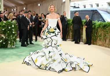 Gigi Hadid na stepenicama Met Gale u skulpturalnoj haljini Thoma Brownea, ukrašenoj žutim ružama i izraženim crnim obrubima. Korzet spuštenih ramena davao je dojam spoja vjenčanog i botaničkog stila, dok je dramatični šlep izgledao kao da je izašla iz bajkovitog vrta. Kamp, visoka moda i obline — sve u punom cvatu.